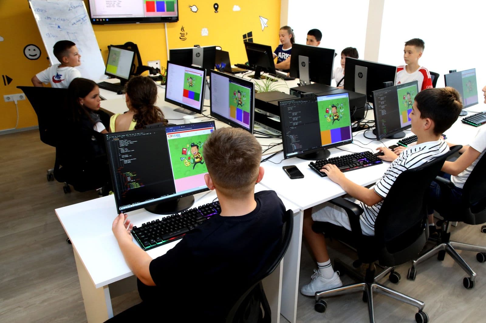 Students writing code in a Romb Academy class, with their web pages open on the screens
