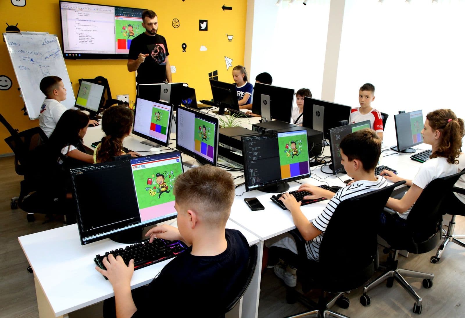 Kinder arbeiten während einer Unterrichtsstunde der Romb Academy an Computern, eine Lehrkraft leitet den Unterricht